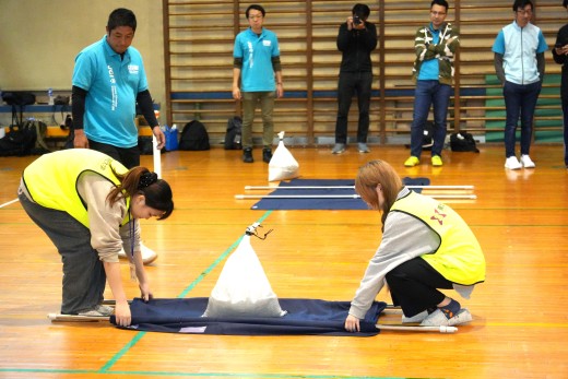 簡易担架で土嚢を運ぶリレーの様子