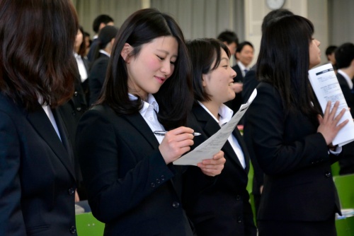 身だしなみを笑顔でチェックしあう、スーツ姿の学生たち