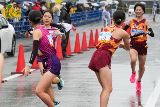 2区村上選手からたすきを受け取る3区佐々木選手（左）