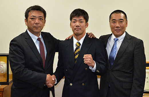 担当の柏田スカウト(左)とガッチリ握手する巨人育成3位指名の笠井選手。右は硬式野球部の大塚監督