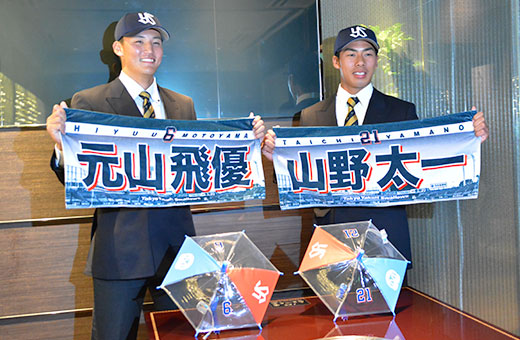 名前と背番号の入ったグッズを手に、報道陣のフラッシュを浴びる山野投手(右)と元山内野手