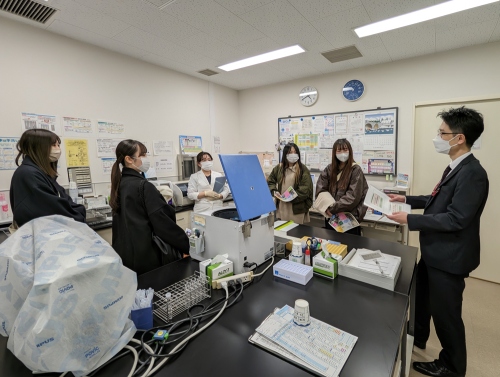 検査室で検査技師の方と事務職の方から説明を受けている様子