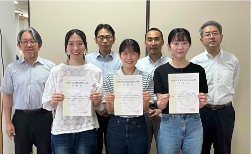 学科教員と合格証を手にした3名の学生