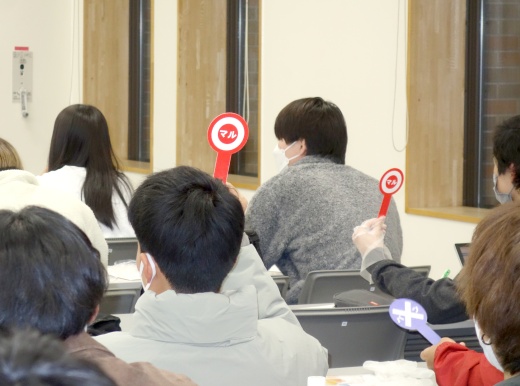 ○×の札をあげて回答する学生たち