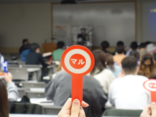 マル・バツの札を挙げてクイズに答える学生たち