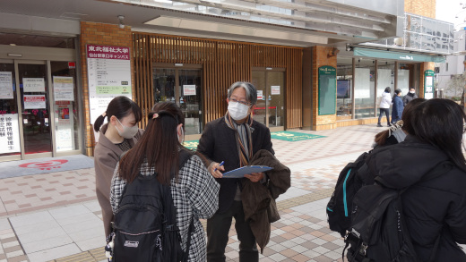 試験会場の入り口前で、渡部先生から激励を受ける学生たち