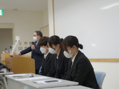 司会の3人と、報告会の進行について説明する渡部教授