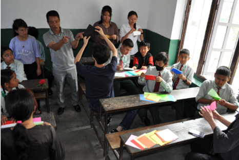 小学校で折り紙を教える学生たち
