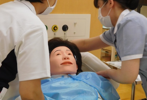 洗髪槽（ケリーパッド）を使用して洗髪を行っています。教員に教わりながら設定していきます。