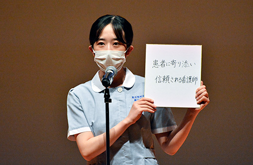 色紙を手に宣誓する学生