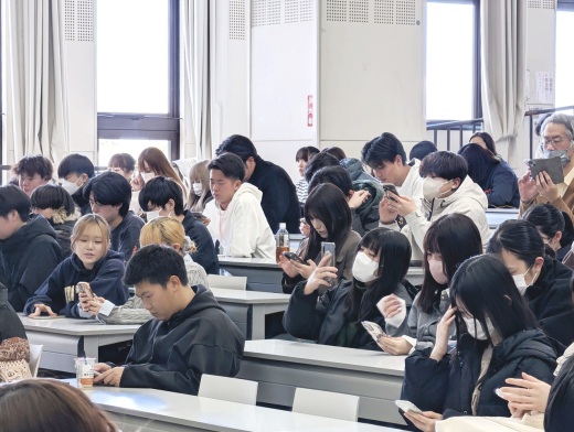 QRコードからフォームにアクセスしてテストの解答を入力している会場の学生たち