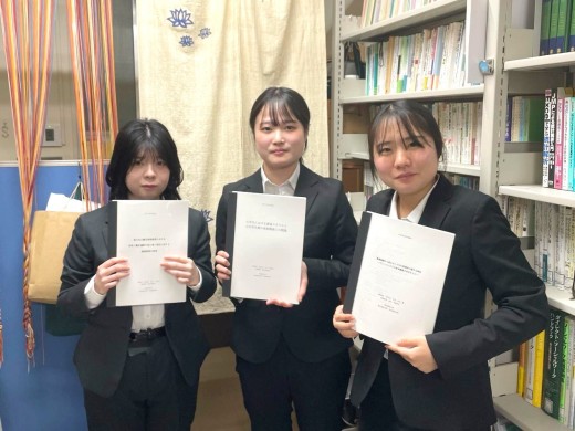清水研究室で卒業論文の冊子を手に記念写真