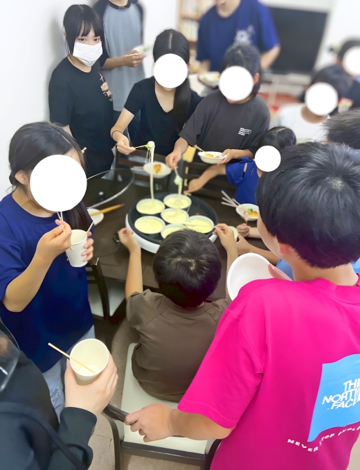 チーズフォンデュを楽しむ子どもたちと見守る学生の様子