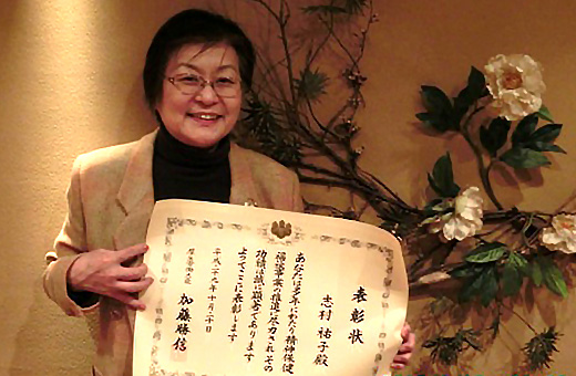 表彰状を手に笑顔の志村准教授