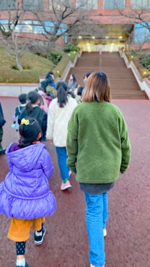 「ひなたぼっこ」から子どもと大学生が一緒に大学に入って行きます