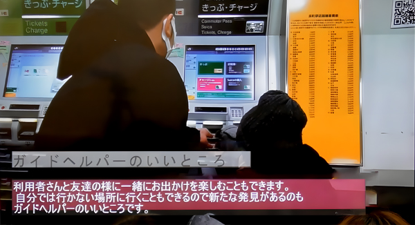 説明会のスライドの一枚。ガイドヘルパーが公共交通機関の切符の券売機で、支援をしている様子