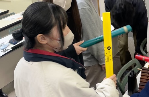 ドレミパイプを2本ぶつけ、和音を出している学生
