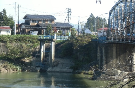 丸森町にある角田用水取り水口（写真中央）と阿武隈川にかかる丸森橋（同右）