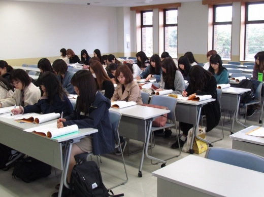 集中してメモを取りながら先輩の発表を聞く2年生
