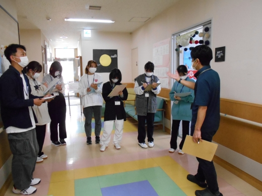 地域ケアステーションの説明を聞きながらメモを取る学生