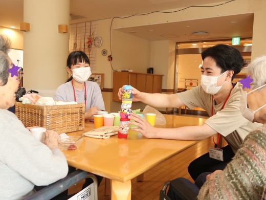 レクリエーション「お手玉タワー」:まずはお手本をみせていますが倒れそう…