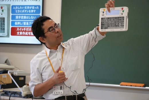意思伝達装置「レッツチャット」を活用した講義を行う髙橋俊史先生