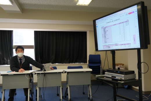 学生便覧を用いて私たちに説明をする三浦さん（遠藤雅直さん撮影）