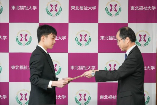 阿部副学長から表彰される新妻さん