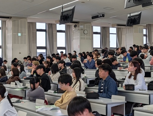 実学ファイルの資料と投影資料を見ながら傾聴する学生