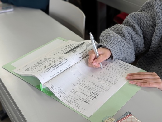 配布された資料に書き込みながら施設紹介を聞いている学生