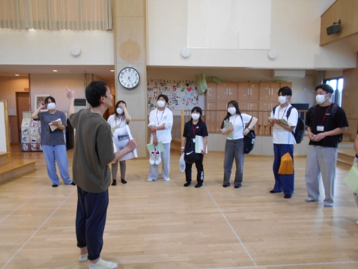 保育園内ホール：保育園の機能・役割の説明を聞いています