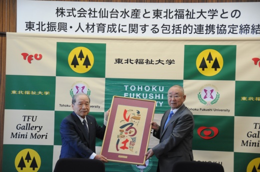協定締結後、大谷学長(右)から芹沢銈介作品を贈呈される島貫会長