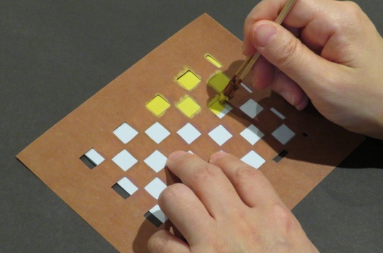 型紙を使って色付けをする様子