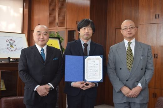 千葉学長（左）と高橋英寛理事長（右）に囲まれたベストティーチャーの青木准教授