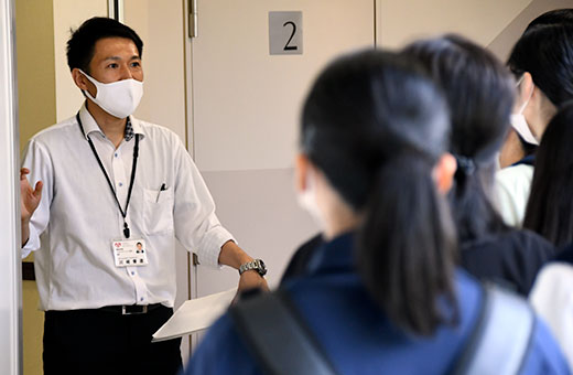 国見ケ丘第1キャンパスのウェルコム21で、施設内を紹介するリハビリテーション学科教員
