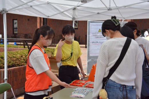 来場者に大学のグッズなどを手渡すオープンキャンパスクラブのメンバー