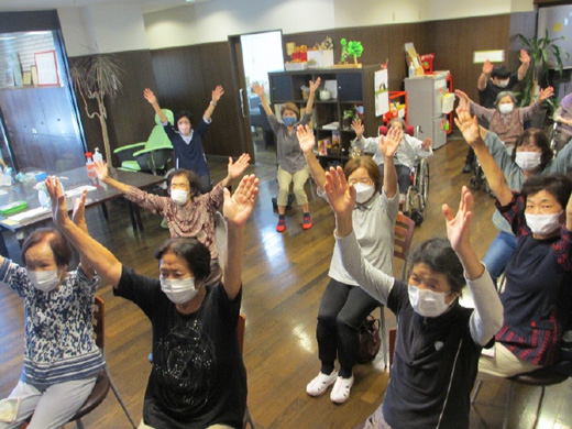 施設のロビーで地域の方々が集い、介護予防体操を行う様子