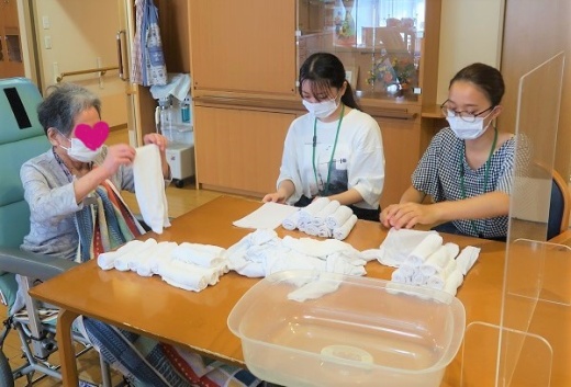 利用者様に教えていただきながらおしぼりタオルをたたんでいます