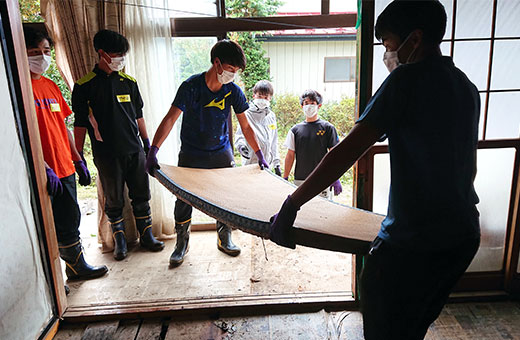 浸水した家屋から水を吸い込んだ畳を運び出す学生たち