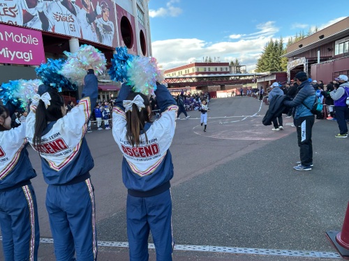 走っている選手をゴールで待つチアリーディング部の学生